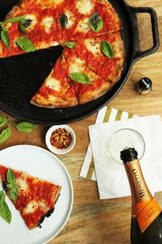 a pizza sitting on top of a pan next to a bottle of wine and two plates