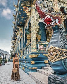 a woman standing in front of a building with an elaborately decorated dragon on it