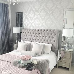 a bedroom with a bed, nightstands and mirror on the wall above it is decorated in silver and gray