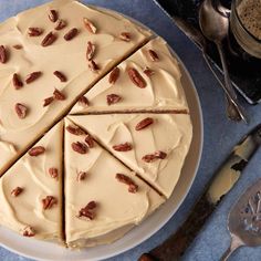 a cake with white frosting and pecans cut into four slices on a plate