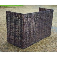 two square wicker baskets sitting on top of a gravel ground next to a green grass field