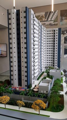 an architectural model of two buildings with trees in the foreground and landscaping on the other side