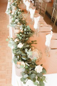 a long table with candles and greenery on the top is set up for a formal function