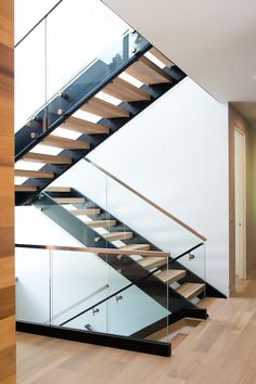 a stair case with glass railing and wooden handrails in a modern style home