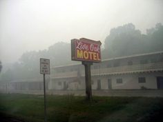 a motel sign in front of a building on a foggy day with no one around it