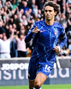 a soccer player running with the ball in his hand and people watching him from the stands