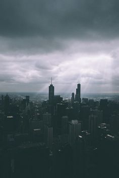 an aerial view of a city with tall buildings and dark clouds in the sky above