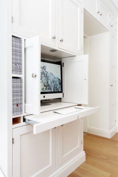 a white desk with a computer monitor on top of it in a room that has wood floors