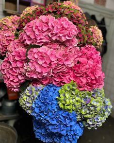 a vase filled with lots of pink and blue hydrangeas on top of a table