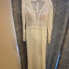 a white lace dress hanging on a curtain