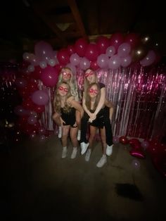 three young women posing for a photo in front of balloons