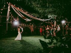 a bride and groom are dancing in front of an audience at their outdoor wedding reception