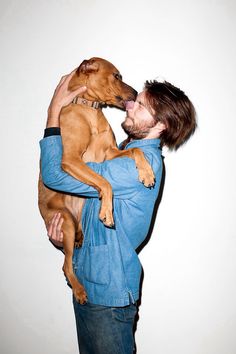 a man holding a brown dog up to his face