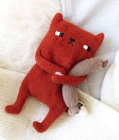 a red stuffed animal laying on top of a white blanket