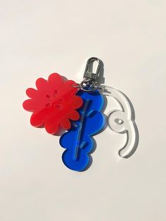 two red and blue flowers are attached to a keychain on a white surface