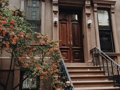 an old building with stairs leading up to the front door and flowers growing on the steps