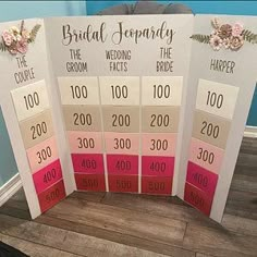 four different colored wedding seating cards with flowers on the front and back sides, sitting on a wood floor next to a blue wall