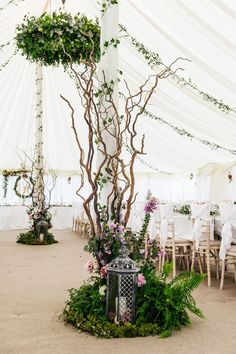 the inside of a marquee decorated with flowers and greenery