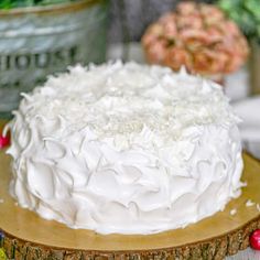 a close up of a cake on a wooden platter with flowers in the background