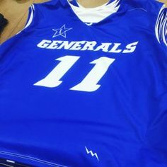 a blue basketball jersey with the number 11 on it sitting on a wooden floor next to a pair of shoes