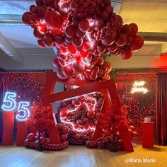 a room with red balloons hanging from it's ceiling and an abstract sculpture on the floor