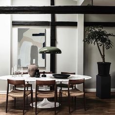 a dining room table with chairs and a vase on the table in front of it