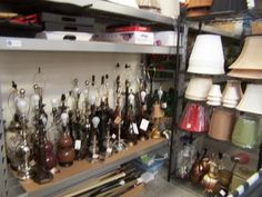 many different lamps are on shelves in a room that is filled with other items and objects