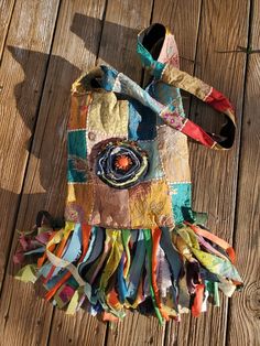 a handbag made out of fabric and ribbons on a wooden floor with a sunflower in the center