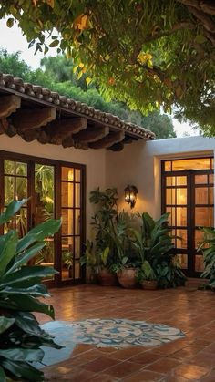 an outdoor patio with potted plants and doors leading to the outside room, surrounded by greenery