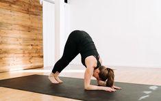 a woman is doing yoga on a mat in the middle of a room with wood walls