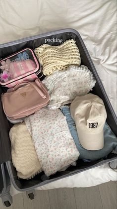 an open suitcase filled with clothing and hats