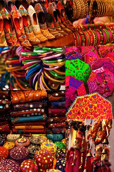 many different types of shoes and umbrellas for sale at a market stall in india