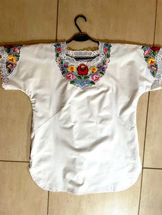 A Unique Handmade white blouse embroidered with authentic Hungarian Kalocsa pattern. A beautiful Hungarian Traditional Handmade Blouse. It was hand embroidered lately by  a unique Hungarian craftswoman. This Hungarian blouse is unique and only, because there is no two identical pieces of handwork. This blouse is an amazing embroidered outfit suitable for many occasions. It can be a gift for mom, sister, wife daughter or the loved ones. It can be a fall outfit for ladies both for a special occasi Traditional White Top With Intricate Embroidery, White Machine Embroidered Blouse For Spring, Traditional White Embroidered Top, Traditional White Blouse With Machine Embroidery, White Traditional Blouse With Machine Embroidery, Embroidered Bohemian Blouse For Traditional Ceremonies, Traditional White Blouse With Embroidered Hem, White Embroidered Top With Geometric Embroidery And Short Sleeves, White Embroidered Top With Geometric Patterns, Short Sleeve