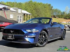 a blue mustang convertible parked in a parking lot