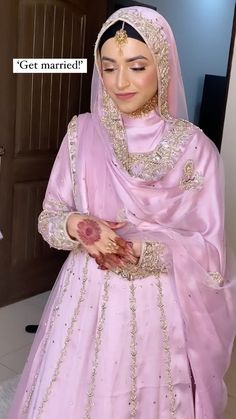 a woman in a pink wedding dress and veil holding her hand out to the side