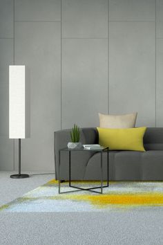 a living room with a gray couch and yellow pillows on the floor next to a lamp