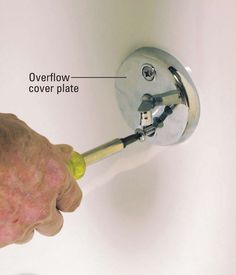 a person's hand is pulling the cover off of a toilet with an overflowing faucet