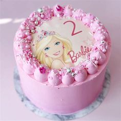 a pink birthday cake decorated with a barbie doll and name on it's top