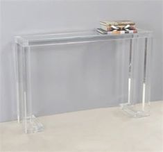 a clear console table with two books on the top and one sitting on it's side