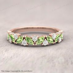 a ring with green and white stones on the sides, set in 18k rose gold