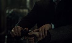 a man in a suit and tie holding a camera with both hands while sitting down