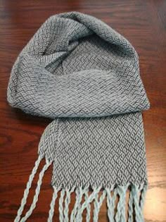 a gray and white scarf sitting on top of a wooden table