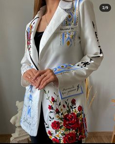 a woman wearing a white jacket with red flowers on the front and blue letters on the back