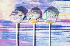 three lollipops sitting on top of each other in front of a colorful background