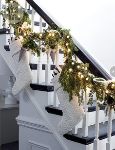 stockings hung on the banisters decorated with christmas lights and greenery, along with garland