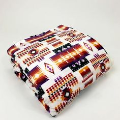 a multicolored blanket is folded on top of each other and sits on a white surface