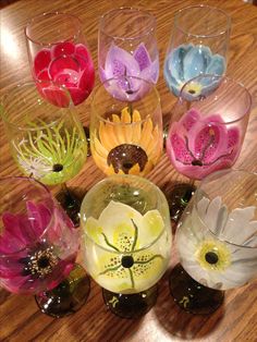 there are many glass vases with flowers in them on the wooden table and one is filled with water