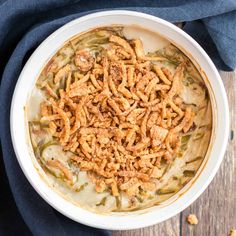 a white bowl filled with green bean casserole on top of a wooden table