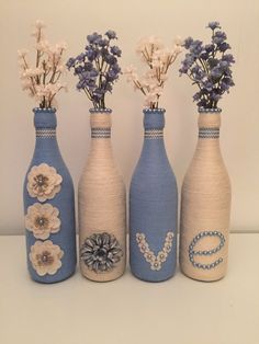 three blue vases with flowers in them sitting on a table next to each other