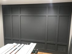 an empty room with black painted walls and wood flooring in the foreground is a workbench that has tools on it